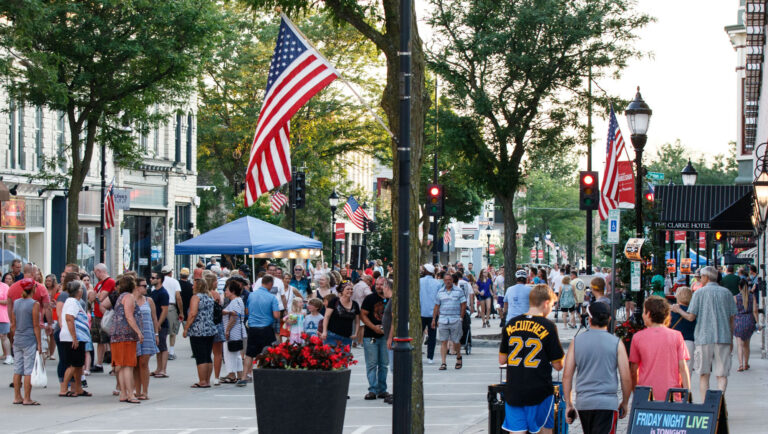 Crowd of people walking downtown at an evening community street festival