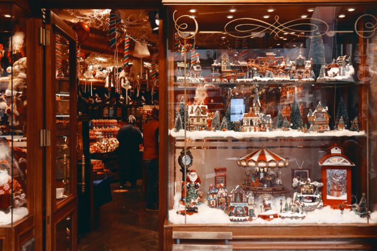 Local shop window decorated for the holidays with Christmas village displays and shoppers inside